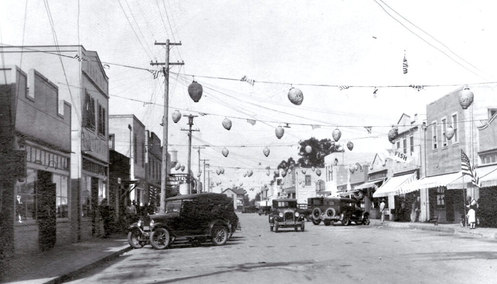 Old cars and balloons fill the road in an old photo of Isleton