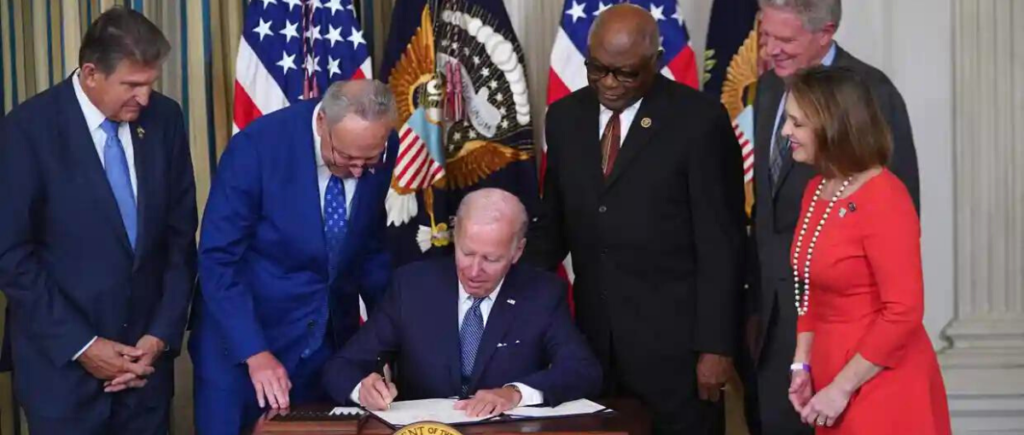 Joe Biden signs the IRA as legislators look on