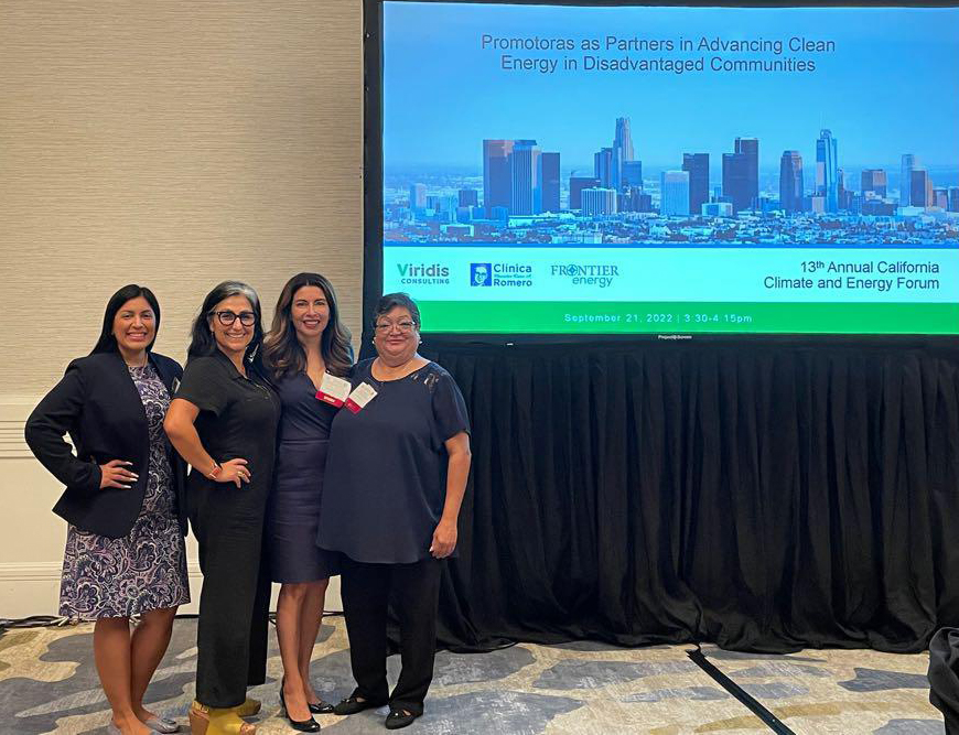 four Latina women stand in front of a screen projector at a conference